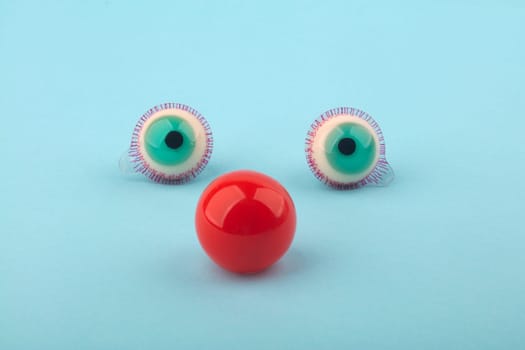 Decorative fruit candy eyes with red nose over light blue background. Conceptual photo using for funny celebration themes.