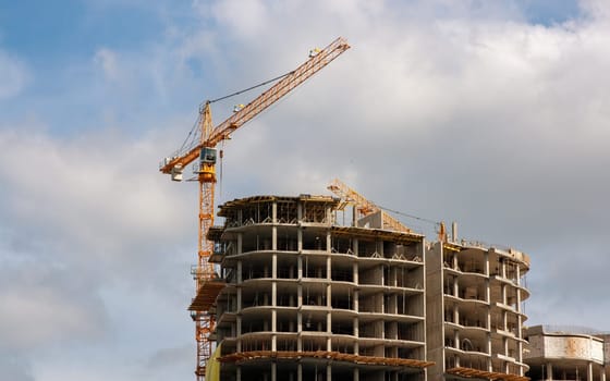Construction. A construction crane and a building under construction. Sky. The clouds