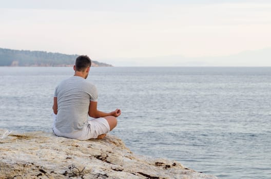 Young man sitting on the coast and meditating