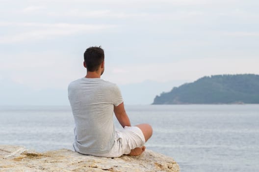 Young man sitting on the coast and meditating