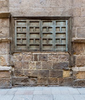 Exterior shot of weathered stone bricks wall and green grunge closed shuttered window on abandoned district