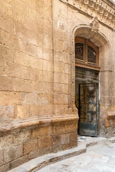 Angled view of grunge door with ferforge wrought iron grill on grunge stone bricks wall in abandoned district