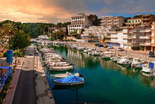Porto Cristo aerial view with harbor, sail ship on a river sourrounded by hotels, reflection on the water, during sunset, Majorca horizontal