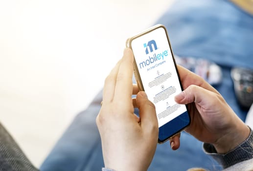 Jerusalem, ISR, March 2022: Woman browsing Mobileye company’s website on her phone. Illustrative editorial. Realistic mockup. Selective focus.