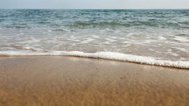 Low angle / ground level photo of wet sand on the beach, sea in background.