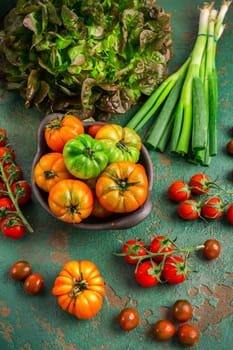 Assortment of tomatoes, lettuce and sprin onions on green background