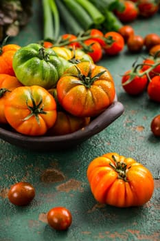Assortment of tomatoes, lettuce and sprin onions on green background