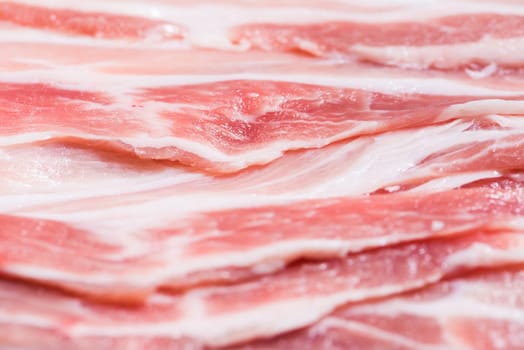 Close up top view pack bacon, pieces raw meat of fresh red pork with white fat slices are sliced into thin strips stacked on top of each other