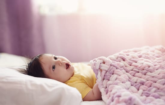 Cute little baby lying under pink blanket. Concept of childhood and maternity.