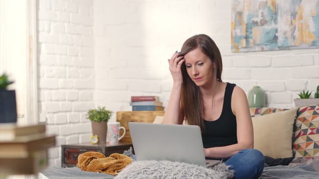 Stay at home and work in home office - Casual woman sitting on bed working online from home with laptop computer.
