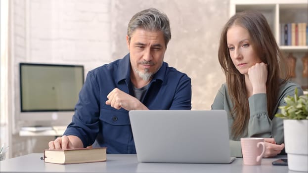 Business people working in office with laptop computer. Happy couple working from home at desk. Talking, meeting, cooperation, entrepreneurs, advisor.