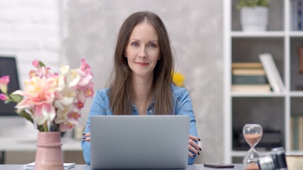 Young woman working online with laptop computer at home sitting at desk. Businesswoman in home office, browsing internet.