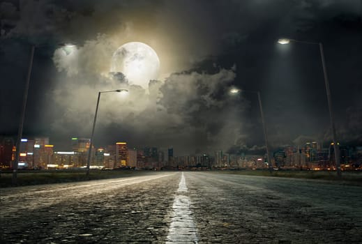asphalt road leading into the city at night
