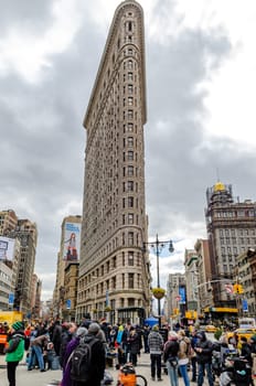 Flatiron Building New York City with lots of People standing in the forefront low angle view during daylight, overcast, vertical