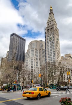 Met Life Tower during daylight, New York City with yellow taxi cab in the forefront, low angle view, vertical