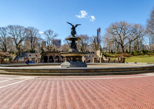 Bethesda Fountain with Angel of the Waters Sculpture rear view, Central Park New York during winter with clear sky, lots of people walking in the background, horizontal