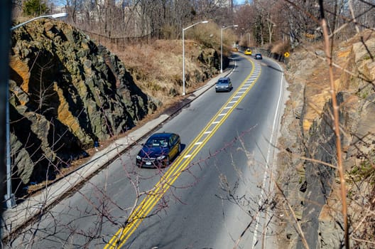 Central Park, New York City, Road with traffic rocks around the street, branches of a tree in forefront, horizontal