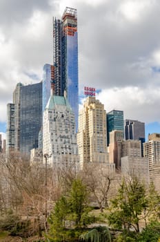 Essex House Building with other Skyscrapers, Skyline of Manhattan on a cloudy winter day, New York City, trees and Central Park in the Forefront, vertical