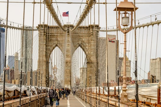 People walking and cycling on Brooklyn Bridge during winter, New York City, Street Light and wire in the forefront, horizontal