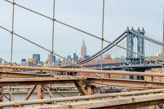 Manhattan Bridge with brown steel construction of Brooklyn Bridge in forefront, New York City, Empire State Building in the Background, horizontal