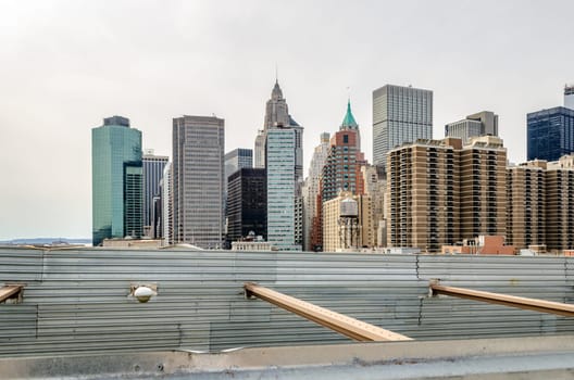Manhattan, New York City with Brooklyn Bridge in forefront, construction area on the Bridge with steel fence, horizontal