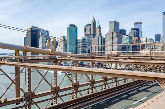 Skyline of Manhattan, New York City with brown steel construction of Brooklyn Bridge in the forefront during daytime in winter, horizontal