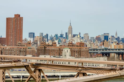 Manhattan Bridge with brown steel construction of Brooklyn Bridge in forefront, New York City, Empire State Building in the Background, horizontal