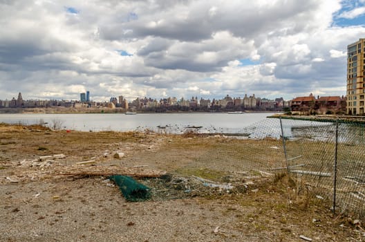 View of Manhattan with Hudson river, Construction area fence and river bank in the forefront, view from North Bergen, New Jersey, during a sunny winter day, horizontal