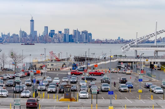 Staten Island Ferry Terminal Parking lot with Skyline of Manhattan, New York City in the Background, lots of different colored cars parking, during winter day with overcast, horizontal