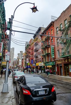 China Town New York City with retail stores and people walking on the sidewalk with umbrella, during rainy winter day with overcast, vertical