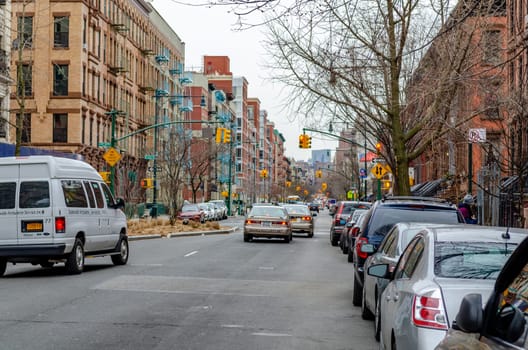 Residential Area, City street with traffic in Harlem, lots of red traffic lights, Lots of cars parked at the street, New York City, during winter day with overcast, horizontal