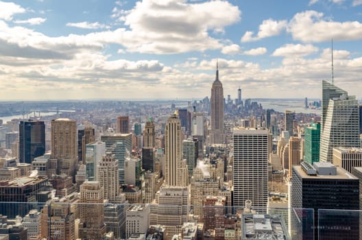 Manhattan Skyline with Empire State Building and Hudson river, aerial view from Rockefeller Center with glass fence in the front, New York City during winter, horizontal