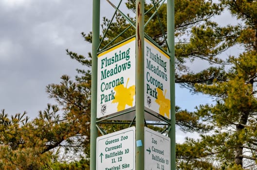 Flushing-Meadows-Corona-Park Sign view from low angle with tree in background, Queens, New York City during overcast winter day, horizontal