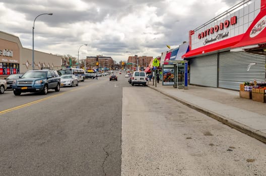 City Street with retail stores in Coney Island, cars parked next to the street, traffic on the street, New York City during winter with overcast, horizontal