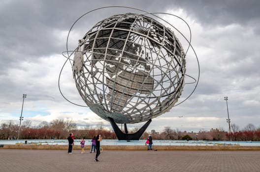 Unisphere at Flushing-Meadows-Park with people standing and walking in front, Queens, New York City during overcast winter day, horizontal