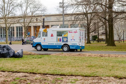 Mister Softee white and blue Ice cream Truck at Flushing-Meadows-Park, Queens, meadow and trees, New York City during overcast winter day, horizontal