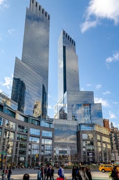 Time Warner Center with people walking on the street in front, New York City, view from low angle during sunny winter day, vertical