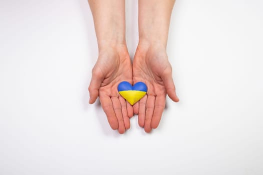 Heart shaped flag of Ukraine in female hands. The concept of solidarity with the citizens of Ukraine.