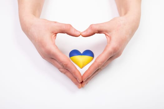 Heart shaped flag of Ukraine in female hands. The concept of solidarity with the citizens of Ukraine.
