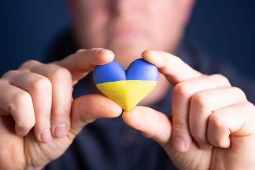 Heart shaped flag of Ukraine in male hands. The concept of solidarity with the citizens of Ukraine.