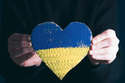 Heart shaped flag of Ukraine in female hands. The concept of solidarity with the citizens of Ukraine.