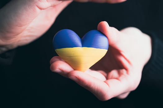 Heart shaped flag of Ukraine in female hands. The concept of solidarity with the citizens of Ukraine.