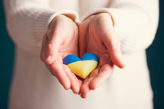 Heart shaped flag of Ukraine in female hands. The concept of solidarity with the citizens of Ukraine.