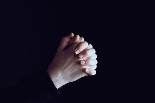 Praying hands with faith in religion and belief in God on dark background. Power of hope or love and devotion.