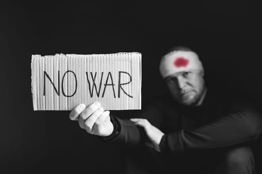 Wounded man holding placard with No war text. Stop war, russian aggression, freedom to Ukraine concept.