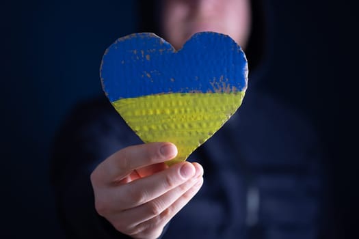 Heart shaped flag of Ukraine in female hands. The concept of solidarity with the citizens of Ukraine.