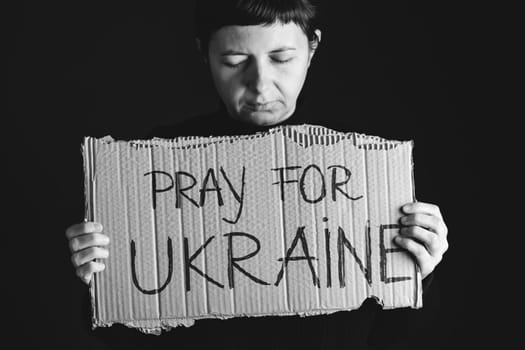 Woman holds a banner with anti-war message. Protest against the Russian intervention to Ukraine, activism and human rights movement. Concept of standing with Ukrainian.