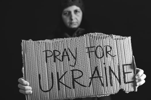 Woman holds a banner with anti-war message. Protest against the Russian intervention to Ukraine, activism and human rights movement. Concept of standing with Ukrainian.