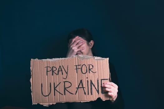 Woman holds a banner with anti-war message. Protest against the Russian intervention to Ukraine, activism and human rights movement. Concept of standing with Ukrainian.