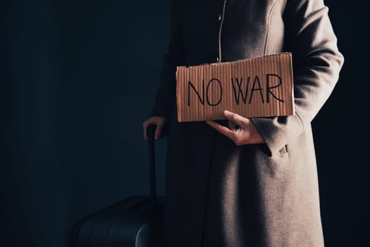 Ukrainian refugee holding placard with No war text. Evacuation of civilians. Freedom to Ukraine concept.